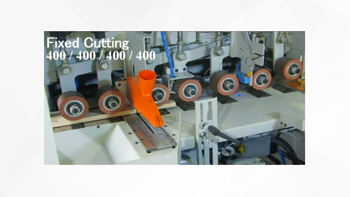 A conveyor system with multiple wooden planks being transported in a woodworking facility, featuring an industrial rip saw for processing the wood.