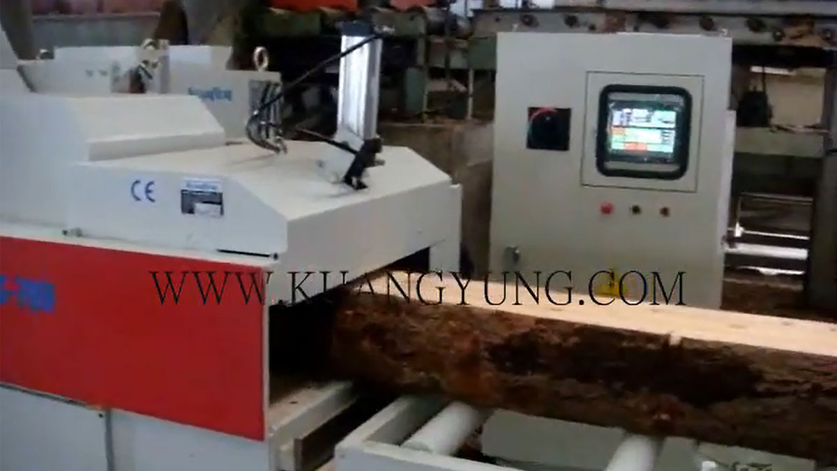 A conveyor system with multiple wooden planks being transported in a woodworking facility, featuring an industrial rip saw for processing the wood.