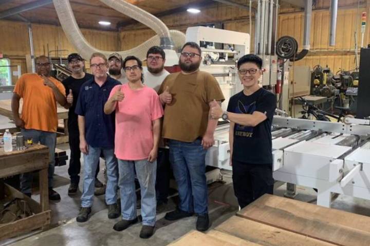 A satisfied woodworking team posing with the Kuang Yung MRS-610M Movable Rip Saw, showcasing its impact on precision and efficiency.