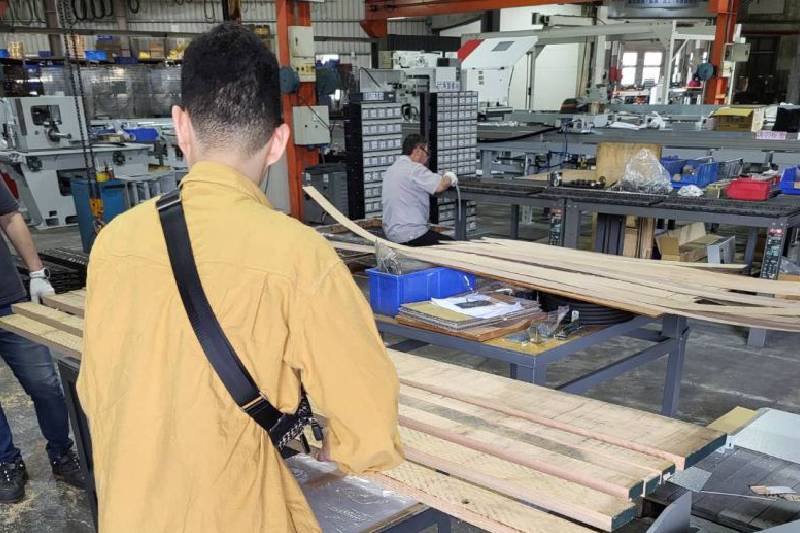 Woodworking professionals inspecting precision-cut wood pieces processed with Kuang Yung's Movable Rip Saw for high-accuracy results.